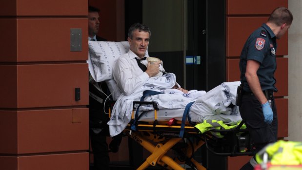 Terry McMaster leaves the Federal Court with the aid of paramedics after collapsing while being questioned.