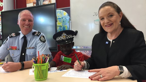 Acting Superintendent Jason Kennedy, North Ainslie Primary School student Chan Arak, 7, and Crime Stoppers ACT region chair Diana Forrester work on the 2018 Crime Stoppers Week colouring in competition.