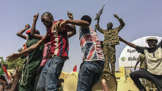 Sudanese men celebrate in April after officials said the military had forced longtime autocratic President Omar al-Bashir to step down.