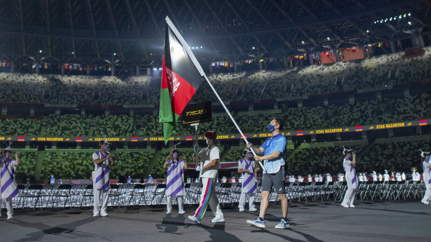 A Paralympic volunteer carries the national flag of Afghanistan during the athlete’s parade.
