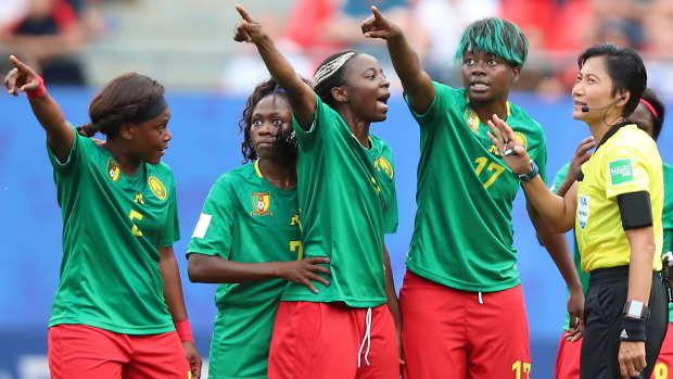 Flashpoint: Cameroon's players argue with referee Qin Liang of China in Valenciennes.