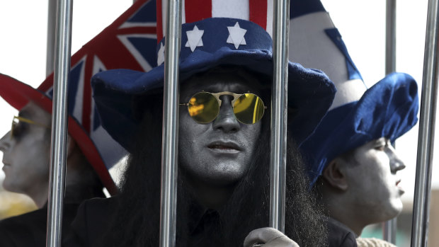 Actors wearing hats in the colours of the flags of Britain, the US and Israel are imprisoned in a cage outside the former US embassy in Tehran.