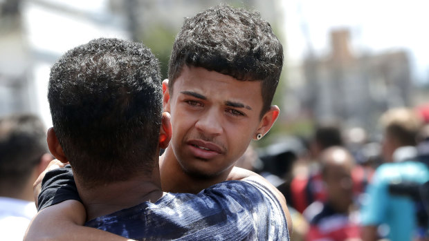 A former student is comforted by a friend outside the Raul Brasil State School in Suzano, Brazil.