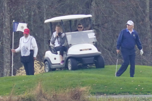 US President Donald Trump, right, plays golf at his club in Sterling, Virginia, on Sunday.