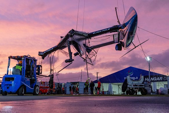 A very broken team New Zealand catamaran is craned out of the water following a collision in Auckland.