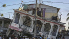 People gather outside the Petit Pas Hotel, destroyed by the earthquake in Les Cayes.