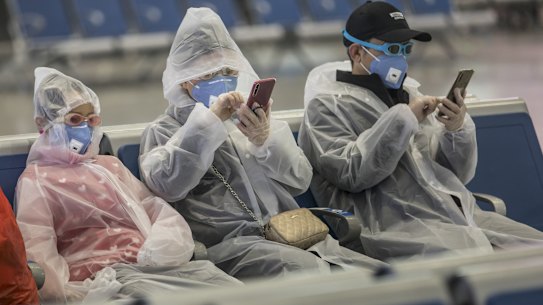 Travellers at a train station in Shanghai wear gear to try to protect themselves from coronavirus.
