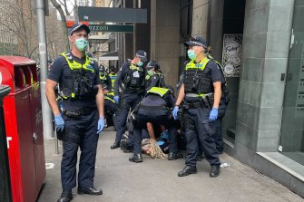 A protester is detained by Victoria Police on Saturday.