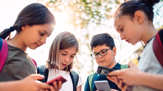 A group of kids playing video games on smartphone after school. 