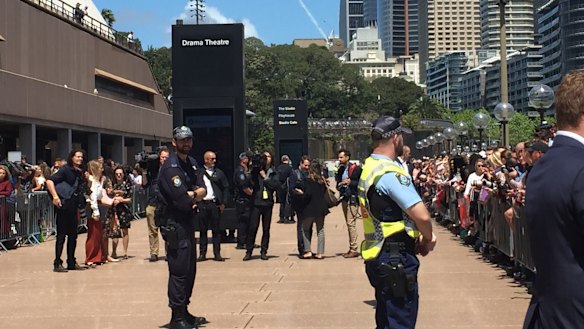 Crowds and security waiting for Harry and Meghan to appear.