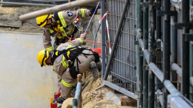 Firefighters in the pit where one man was killed and two were injured.