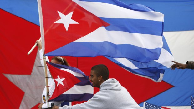 A man rides in the back of a pick-up truck waving Cuban flags in Florida. The US has also recalled its diplomats.