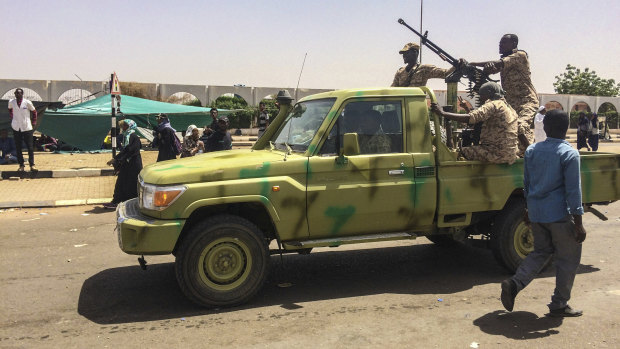 Sudanese army soldiers patrol near protesters gathered near the military headquarters.