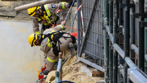 Firefighters at the top of the pit where one man was killed and two were injured.
