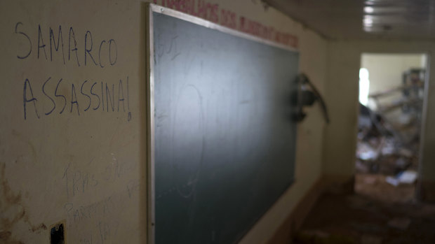 A scrawled message in Portuguese that reads "Samarco Assassin" rests on a classroom wall a year after the school was destroyed by a tsunami of mud triggered by the tailings dam failure.
