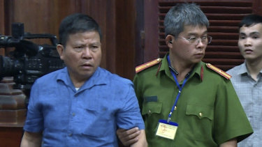 Australian man Chau Van Kham, left, is escorted into a Vietnamese court.
