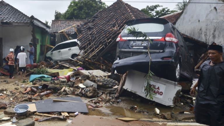 People inspect the damage at a tsunami-ravaged neighbourhood in Carita.