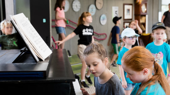 Students play a grand piano during lunch time at Lindfield Learning Village