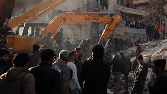 Emergency services work at a building hit by an air strike in Damascus blamed on Israel.