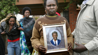 A photo of  Liep Gony is held by his mother Martha Ojulo, while his distressed girlfriend is supported during a press conference in 2007.