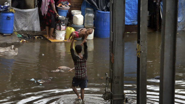 A man holds a child above his head as he wades through a waterlogged street in Mumbai.