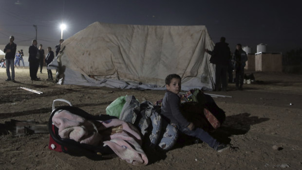 A Palestinian boy sits over his family's belongings next to tents set up near the Gaza Strip border with Israel.