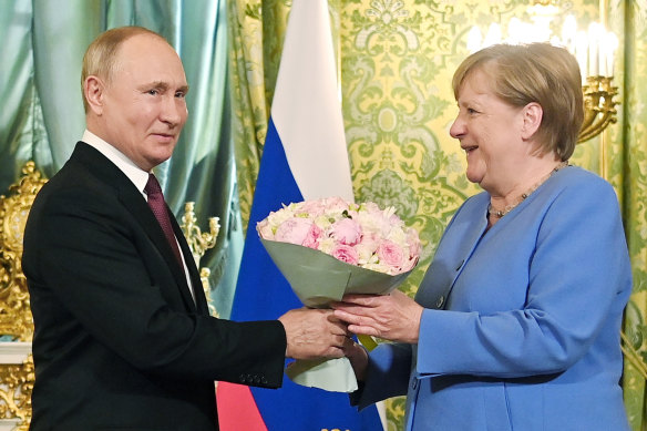 No dogs this time: Russian President Vladimir Putin, left, presents flowers to German Chancellor Angela Merkel during their meeting in the Kremlin on Friday.