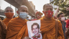 Thai monks wearing masks hold a portrait of Aung San Suu Kyi  during a demonstration.