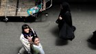An Iranian woman without her Islamic headscarf flashes a victory sign as a veiled woman passes at the old main bazaar of Tehran.