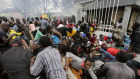 Kenyan residents desperate for a planned distribution of food stampede through a gate on April 10.