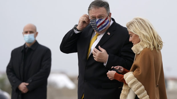 US Secretary of State Mike Pompeo adjusts his mask as he prepares to board a plane at Paris Le Bourget Airport standing with US Ambassador to France Jamie McCourt.