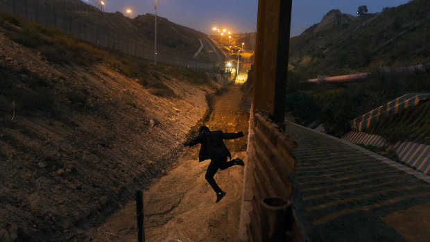 A Honduran youth jumps from the US border fence in Tijuana, Mexico, before Christmas.