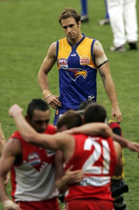 A dejected Chris Judd looks on as Sydney celebrates the 2005 grand final victory over West Coast.