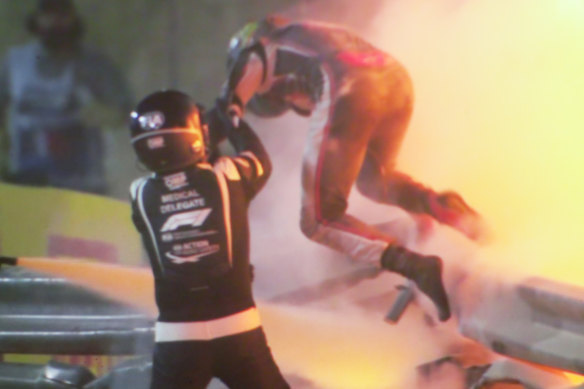 Romain Grosjean is helped from his burning car by marshals. 