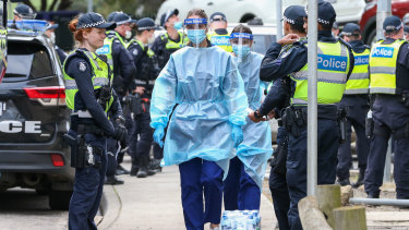 Medical staff wearing PPE holding material about to walk into the Flemington public housing flats on Sunday.