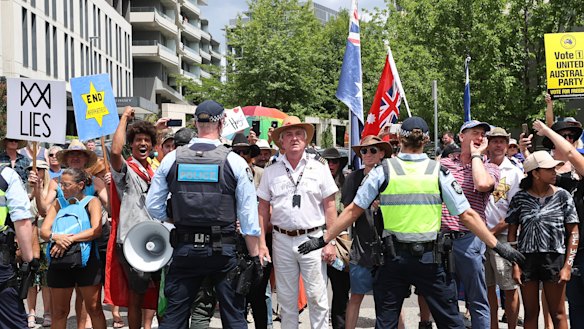 Former Qantas pilot Graham Hood (centre) stands among a crowd of protesters facing off with police on Tuesday.