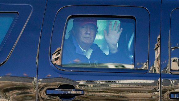 US President Donald Trump waves to supporters from his motorcade as people gather for a march in Washington.