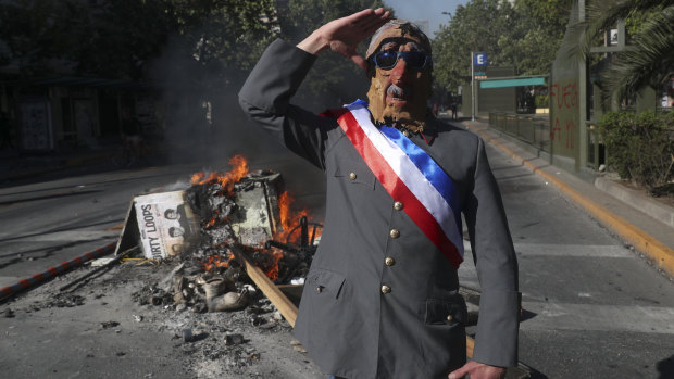 An anti-government demonstrator disguised as late military dictator General Augusto Pinochet salutes in Santiago on Wednesday.