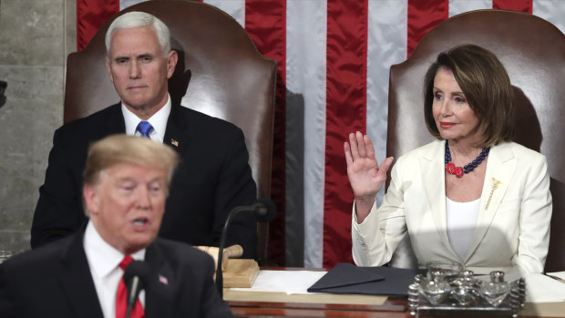 Pelosi raises her hand in a gesture to quiet the Democrats.