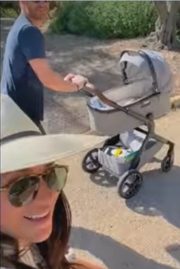 Meghan beside Harry, who is pushing a pram.