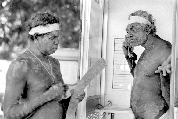 Jimmy Numbato, watched by Jacob Miler, uses a new phone at Daly River Crossing in the Northern Territory in 1985.
