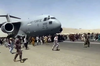 Hundreds of people run alongside a US Air Force C-17 transport plane at Kabul airport on Monday.