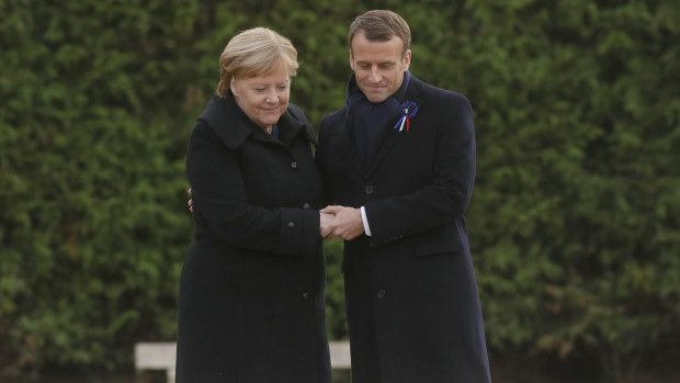French President Emmanuel Macron and German Chancellor Angela Merkel hold hands after braving the rain to unveil a plaque in the Clairiere of Rethondes.