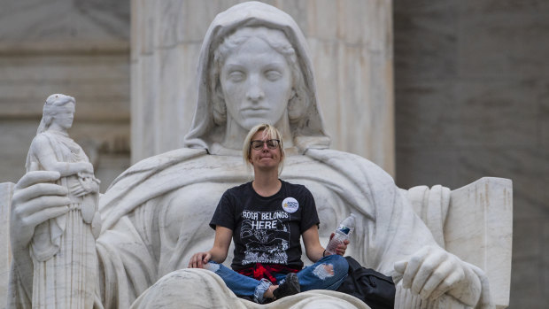 Jessica Campbell-Swanson, an activist from Denver, sits in the lap of a sculpture known as the Statue of Contemplation of Justice on the steps of the Supreme Court Building where she and others protested the confirmation of Brett Kavanaugh as the high court's newest justice, in Washington, on Saturday.