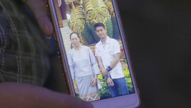 The aunt of coach Ekapol Chanthawong shows a picture of the coach and his grandmother on a mobile phone screen.