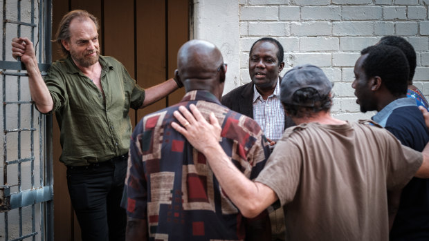 Playing a war photographer, Hugo Weaving listens to an African choir featuring a South Sudanese refugee played by Andrew Luri (facing camera) in Hearts and Bones. 