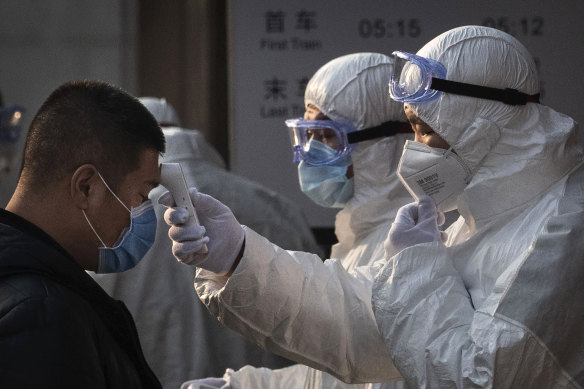 A Chinese health worker checks the temperature of a man entering a subway station during the Chinese New Year and Spring Festival in Beijing on Saturday.