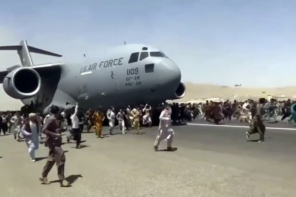 Hundreds of people run alongside a US Air Force C-17 transport plane at Kabul airport on Monday.