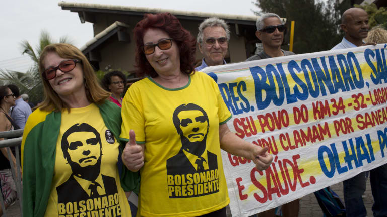Supporters of President-elect Jair Bolsonaro wear T-shirts with his image, outside Bolsonaro's home where he was holding meetings in Rio de Janeiro on Thursday.