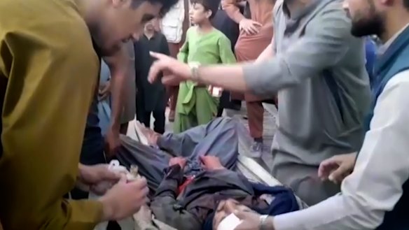 People try to help a wounded man near the site of one of the bombings outside Kabul airport.